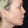 A close-up side profile of a person with blonde hair and fair skin. They are wearing a small hoop earring in their left ear. The background is plain and dark, directing focus to the person's facial features.