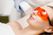 A woman wearing orange protective eyewear receives a facial treatment with a laser device handled by a person wearing gloves.