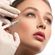 A close-up of a woman receiving a facial injection from a syringe held by a person wearing medical gloves, focusing on beauty treatment.