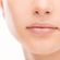 Close-up of the lower half of a person's face with smooth, clear skin, showing the nose, cheeks, and closed lips. The background is plain white.
