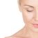 Close-up of a woman's face with her eyes closed. The image captures the right side of her face, showing smooth skin, neatly groomed eyebrows, and light makeup. She appears serene, with a soft smile. The background is a plain white.