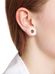 A close-up of a person's ear with a white earlobe plug and a small ear stud. The person has light skin, and part of their brown hair and white clothing collar are visible. The background is white.